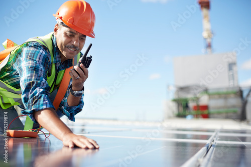 Engineer with walkie-talkie inspecting solar panel at power plant
