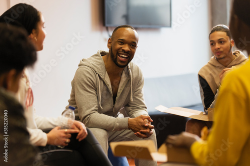 Smiling male mentor talking to teenagers in youth organization photo