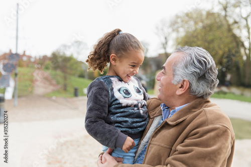 Smiling grandfather holding granddaughter at park
