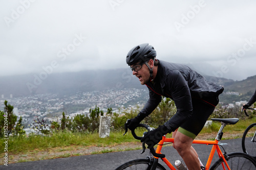 Determined male cyclist cycling on rainy road photo