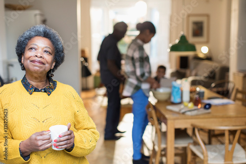 Smiling, satisfied senior woman drinking coffee with family 