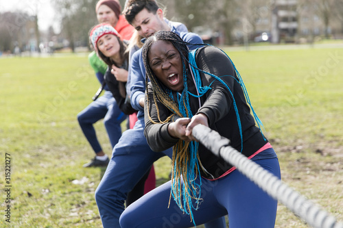 Determined team pulling rope in tug-of-war at park photo