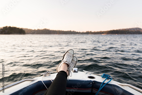 Personal perspective woman boating with feet up on tranquil lake