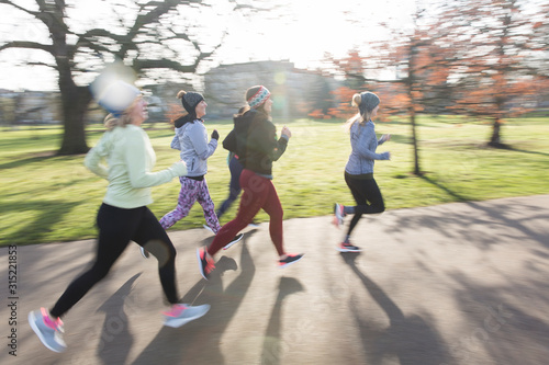 Female runners running in sunny park photo