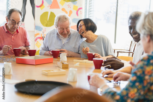 Happy senior friends playing games at table in community center photo