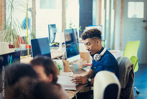 Creative businessman working at computer in open plan office photo