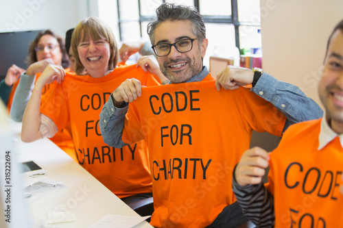 Portrait confident hackers in t-shirts coding for charity at hackathon photo