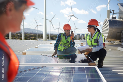 Engineers examining solar panels at alternative energy power plant photo