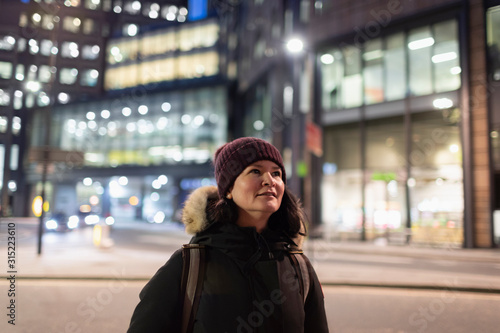 Woman in warm clothing walking on urban street at night photo