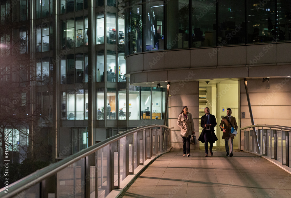 © Paul Bradbury/Caia Image - Business people walking on urban pedestrian bridge at night