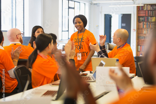 Hackers cheering for woman, coding for charity at hackathon photo