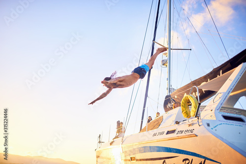 Young man diving off catamaran photo