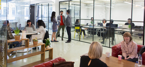 Creative business people talking in open plan office photo