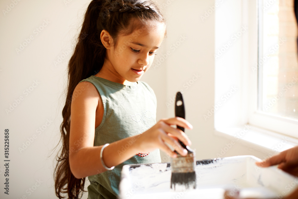 Girl painting, dipping paintbrush in tray Girl painting, dipping paintbrush in tray
