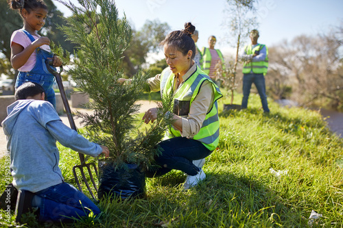Woman and children volunteers planting tree at sunny campsite