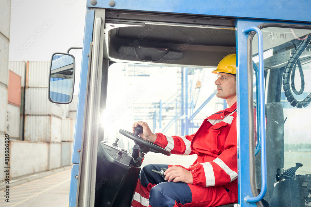Dock worker operating cargo container forklift at shipyard Dock worker operating cargo container forklift at shipyard