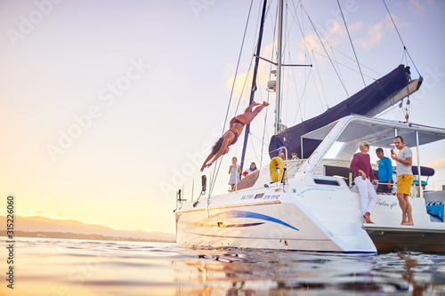 Young woman diving off catamaran into ocean photo