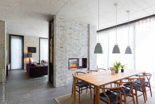 Pendant lights over dining table in modern dining room with fireplace