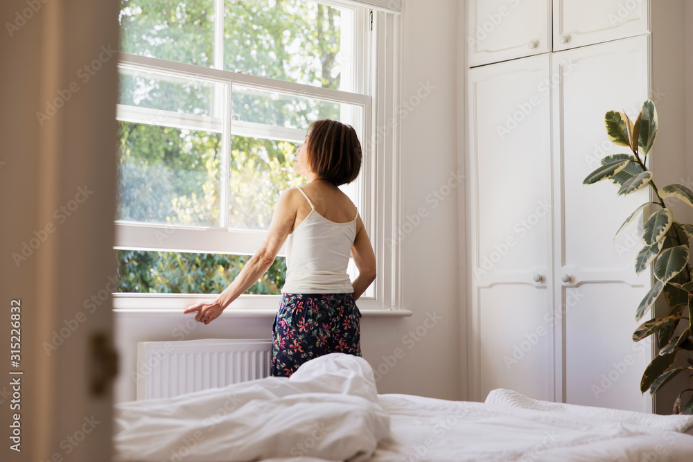 Thoughtful senior woman looking out bedroom window Thoughtful senior woman looking out bedroom window