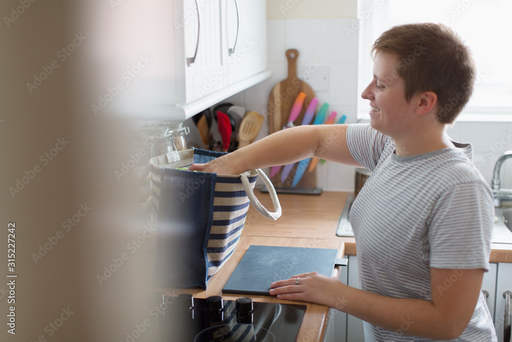 © Martin Barraud/Caia Image - Young woman unpacking groceries in apartment kitchen © Martin Barraud/Caia Image - Young woman unpacking groceries in apartment kitchen