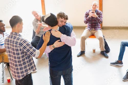 Men hugging and clapping in group therapy photo