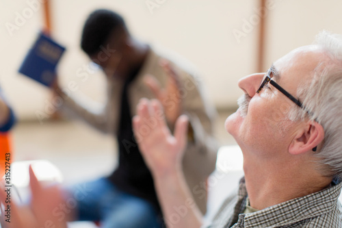 Senior man with head back praying in prayer group