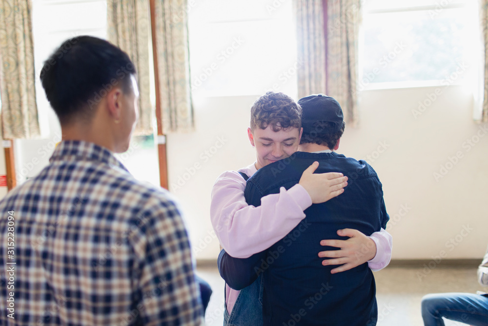 Men hugging in group therapy Men hugging in group therapy
