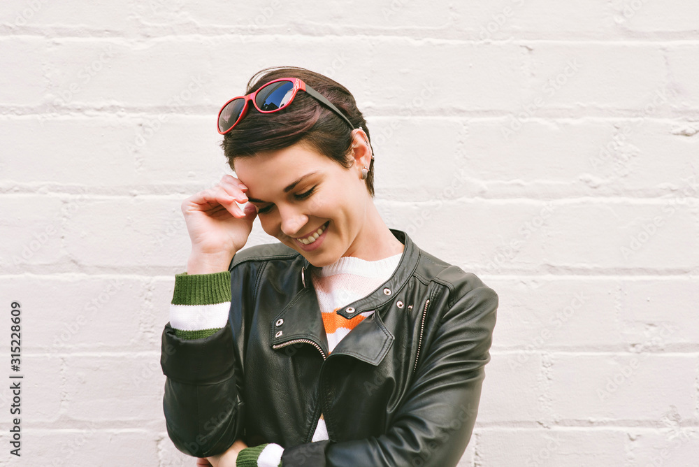 Pretty Caucasian woman smiles while looking down and away with sunglasses on her head - Short hair millennial female - Concept happiness Pretty Caucasian woman smiles while looking down and away with sunglasses on her head - Short hair millennial female - Concept happiness