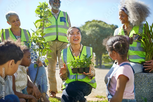 Happy volunteers planting trees and plants in sunny park