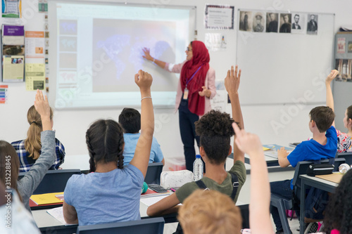 Female teacher in hijab teaching lesson at projection screen in classroom photo