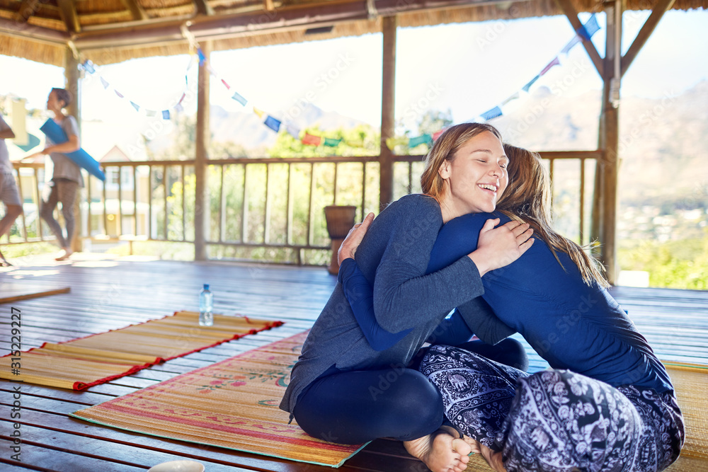 Happy mother daughter hugging on yoga mats in hut during yoga retreat Happy mother daughter hugging on yoga mats in hut during yoga retreat