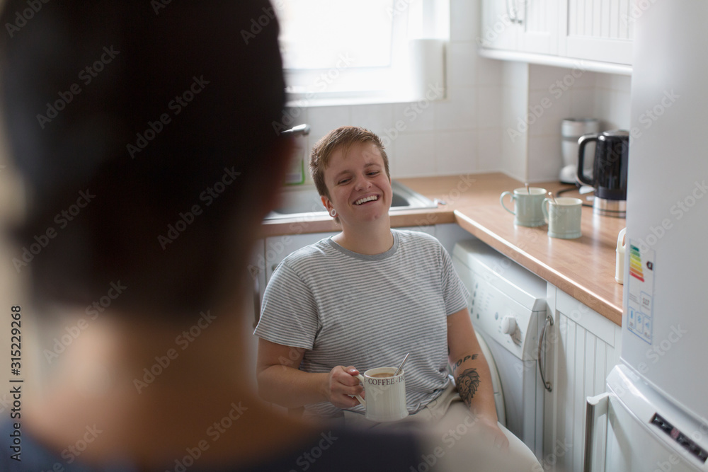 Happy young woman in wheelchair drinking tea in apartment kitchen Happy young woman in wheelchair drinking tea in apartment kitchen
