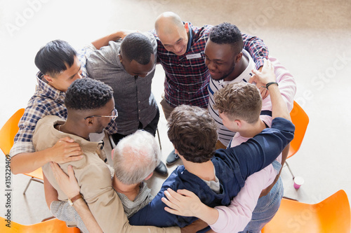 Men hugging in huddle in group therapy photo