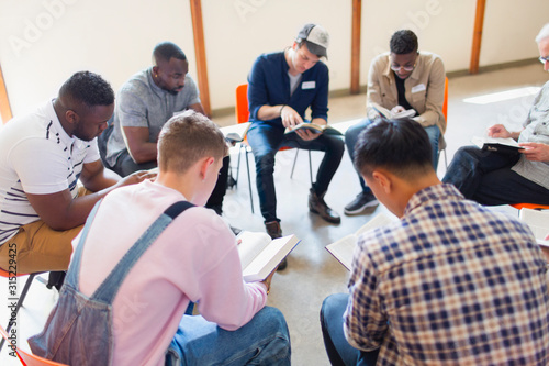 Men reading and discussing bible in prayer group photo