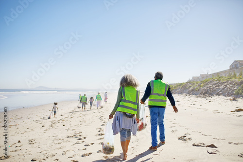 Volunteers cleaning up litter on sunny, sandy beach