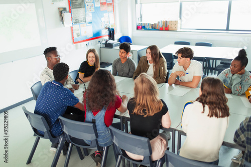 High school students talking in debate class at table in classroom