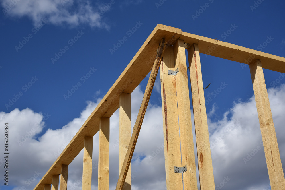 Wood frame residential building under construction.Building construction, wood framing structure at new property development site.new home currently under construction against blue sky.mortgage, loan. Wood frame residential building under construction.Building construction, wood framing structure at new property development site.new home currently under construction against blue sky.mortgage, loan.