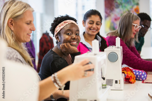Portrait confident female fashion designer working at sewing machine
