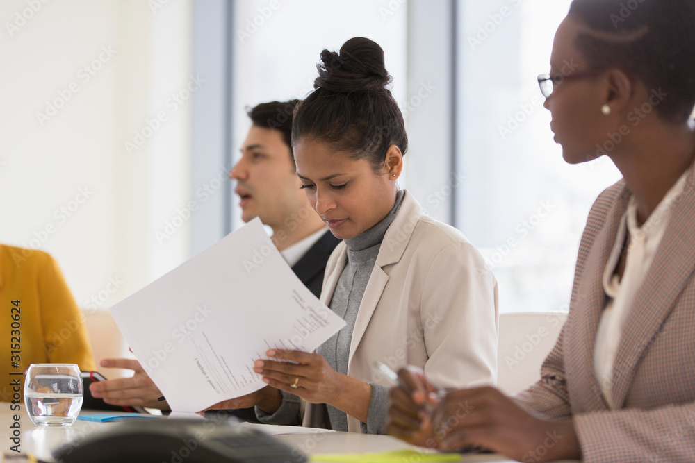 Businesswoman reviewing paperwork in conference room meeting Businesswoman reviewing paperwork in conference room meeting