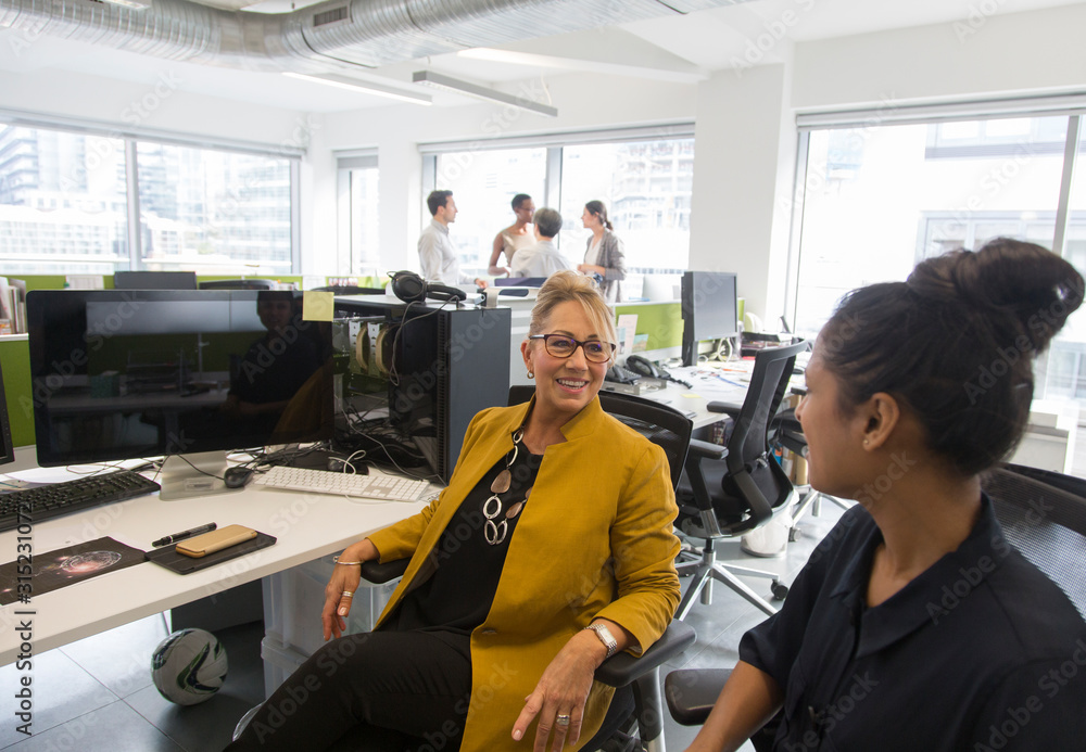 Businesswomen talking in open plan office Businesswomen talking in open plan office