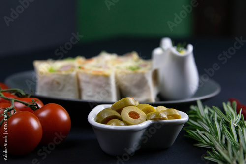 Pita on a beautiful gray plate, next to there are cherry tomatoes, rosemary, olives, and red hot pepper photo