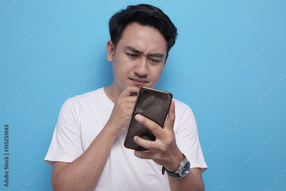 Young Man Thinking While Chatting on Smart Phone Young Man Thinking While Chatting on Smart Phone