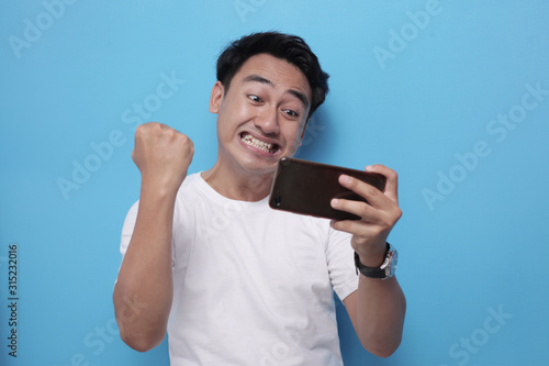 Funny Young Asian Guy Playing Games on Tablet © airdone