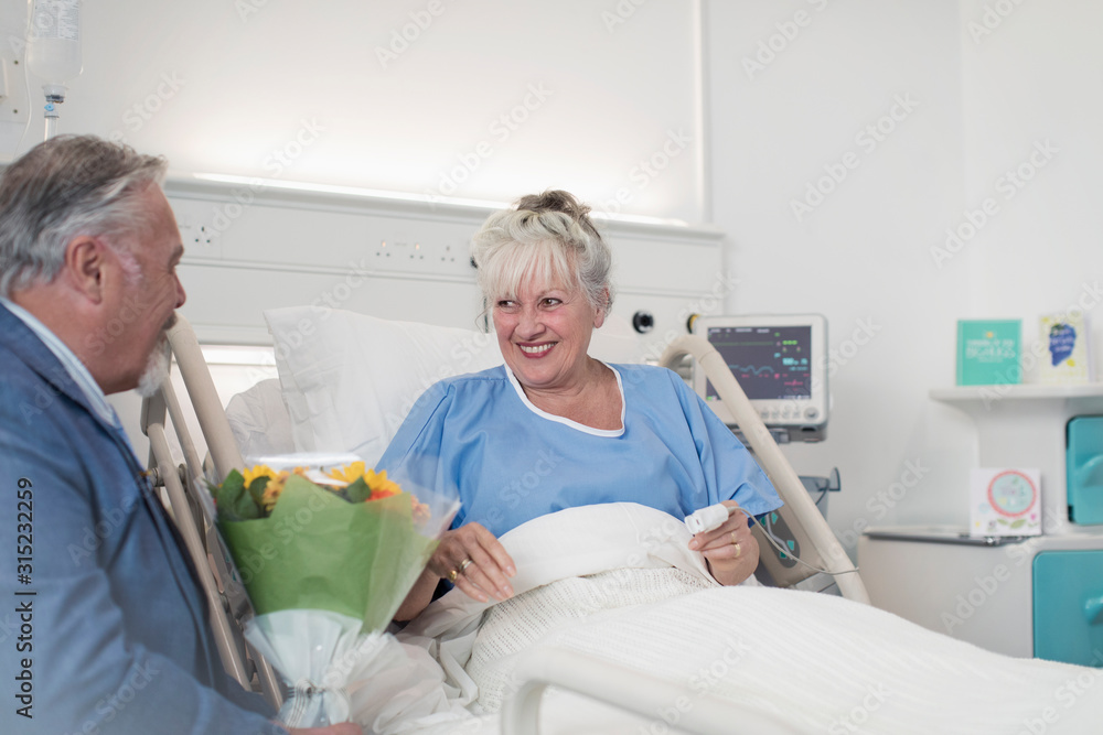 Senior man with flower bouquet visiting wife in hospital Senior man with flower bouquet visiting wife in hospital
