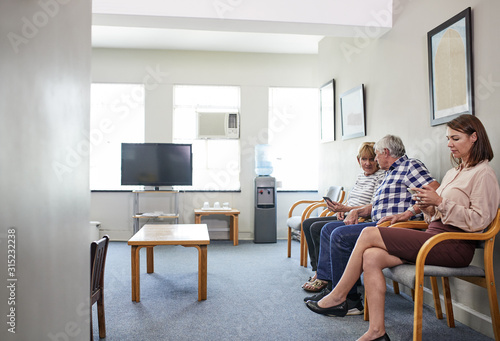 Patients waiting, using smart phones in clinic waiting room