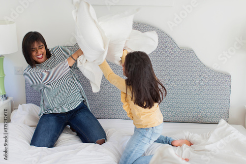 Playful mother and daughter enjoying pillow fight photo