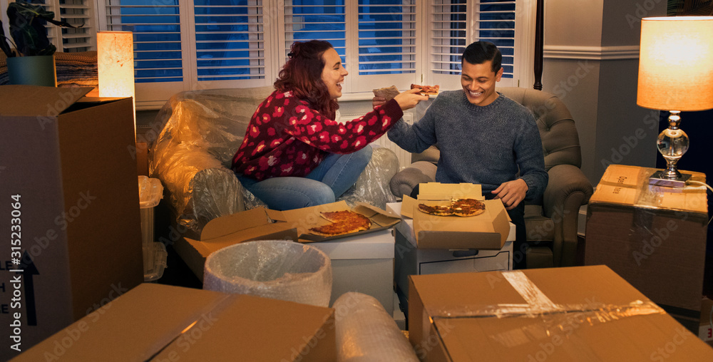 Happy couple taking a break from moving, eating pizza Happy couple taking a break from moving, eating pizza