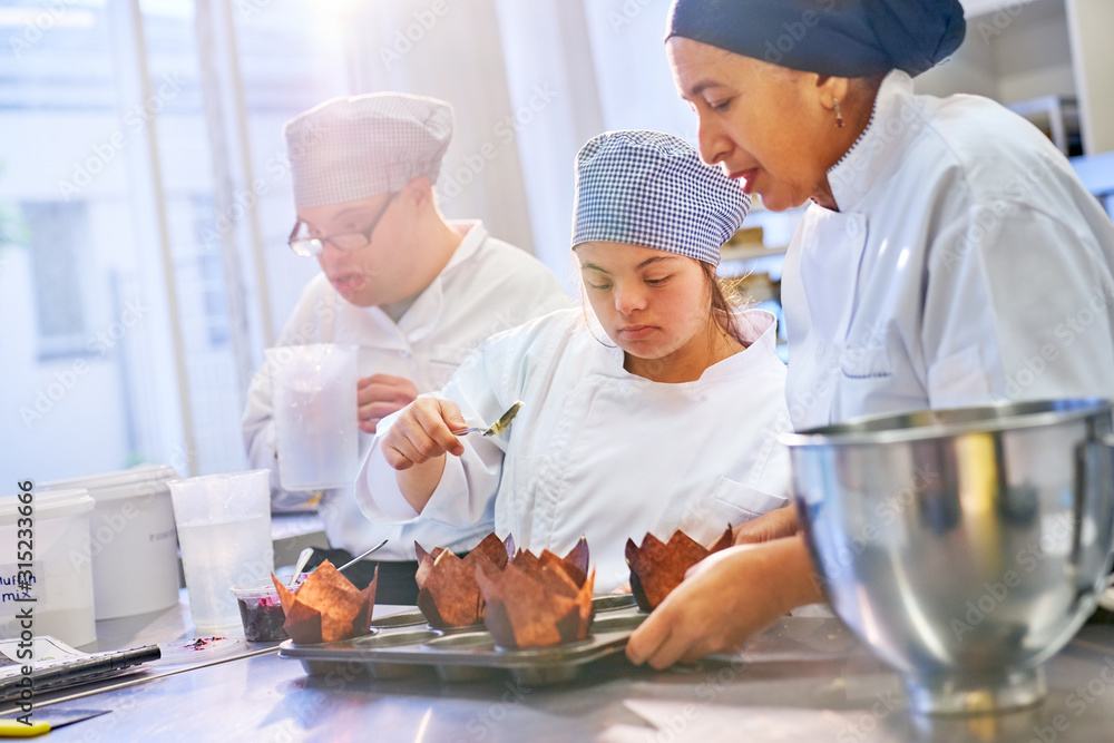 Chef and young woman with Down Syndrome baking muffins Chef and young woman with Down Syndrome baking muffins