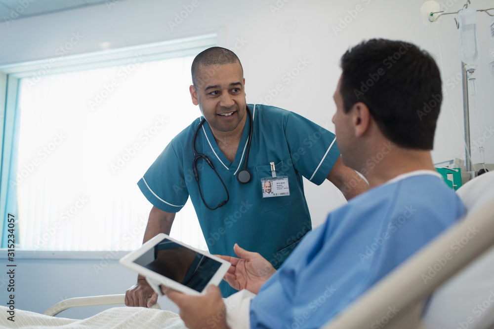 Male nurse talking with patient using digital tablet in hospital bed Male nurse talking with patient using digital tablet in hospital bed