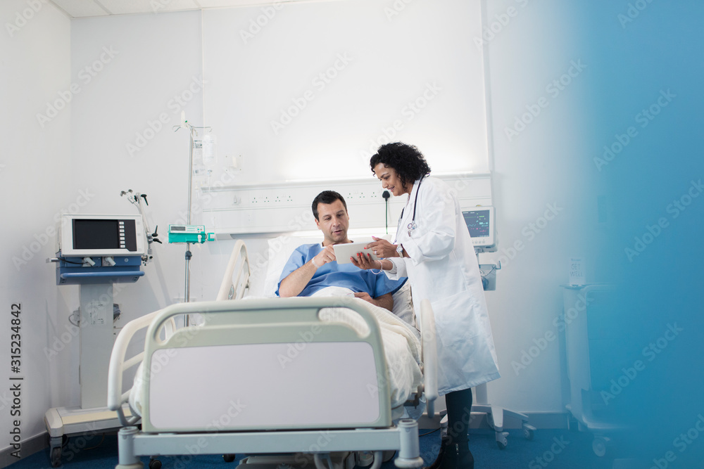 Doctor with digital tablet making rounds, talking with patient resting in hospital bed Doctor with digital tablet making rounds, talking with patient resting in hospital bed